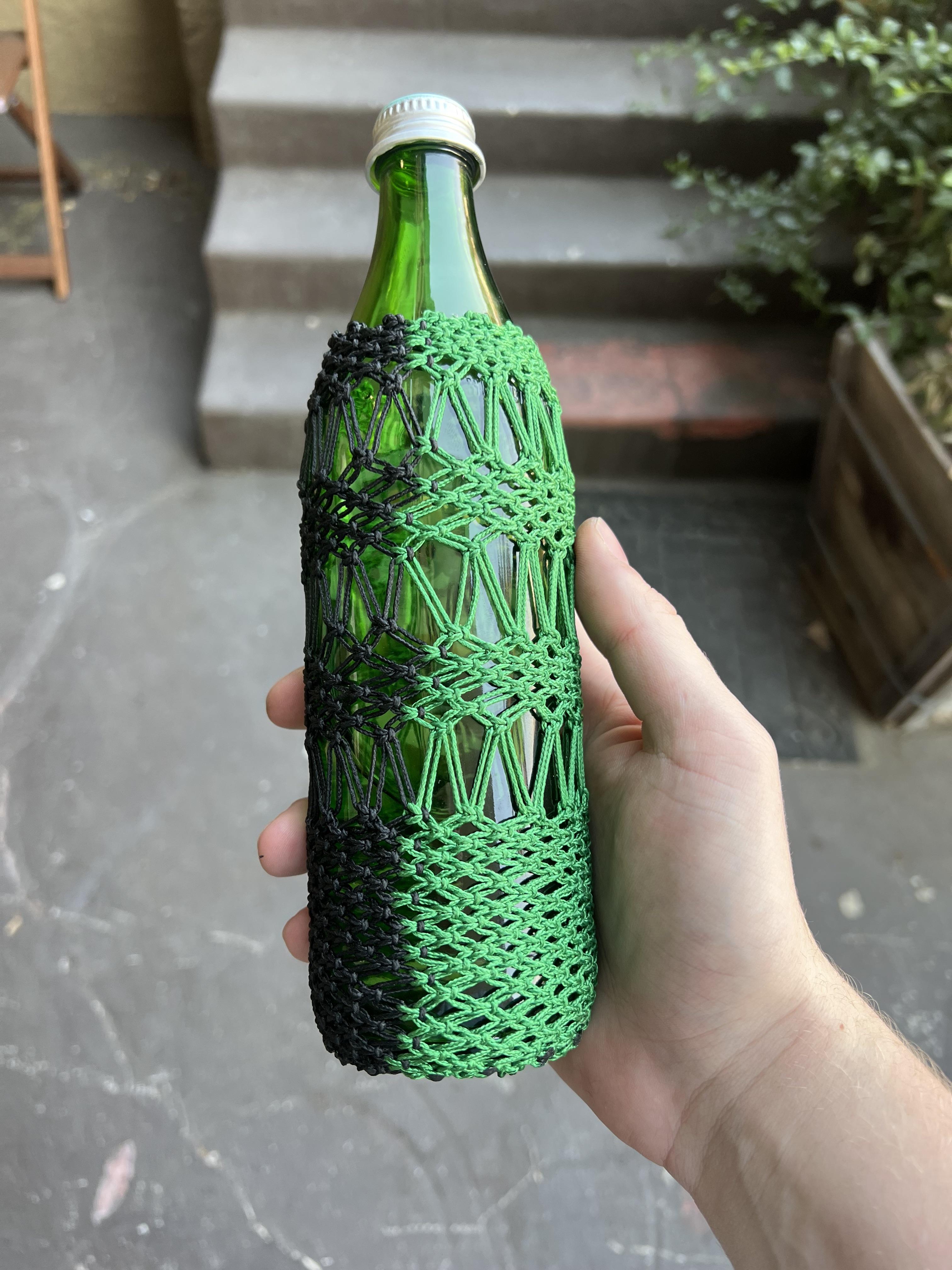 Green glass bottle in a green and black macramé sleeve